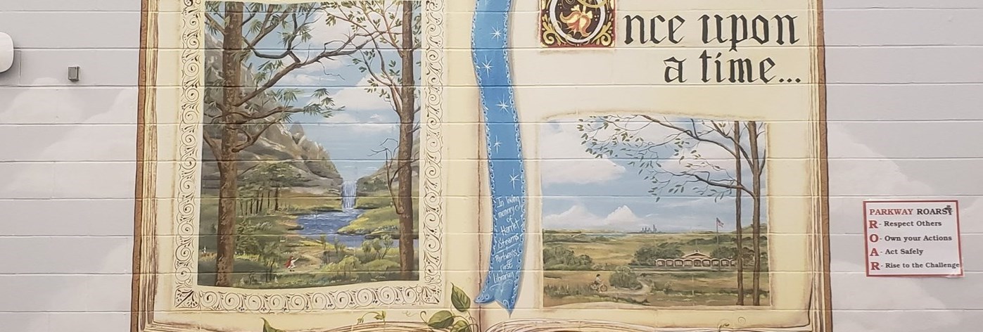 Mural of a book with Once a  upon a Time painted on a wall. two images are illistrated, 1st is of a lanscape with trees and a river, 2nd is of a Plain landscape