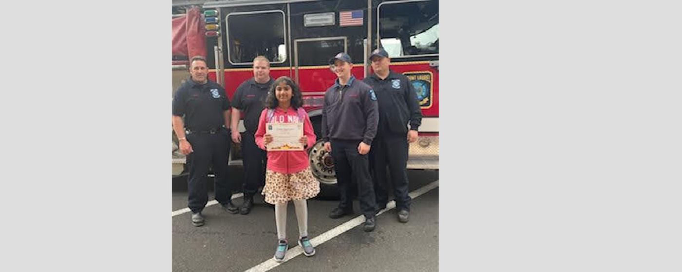 Fired up for Literacy 4th grade winner standing with Firefighters and fire engine
