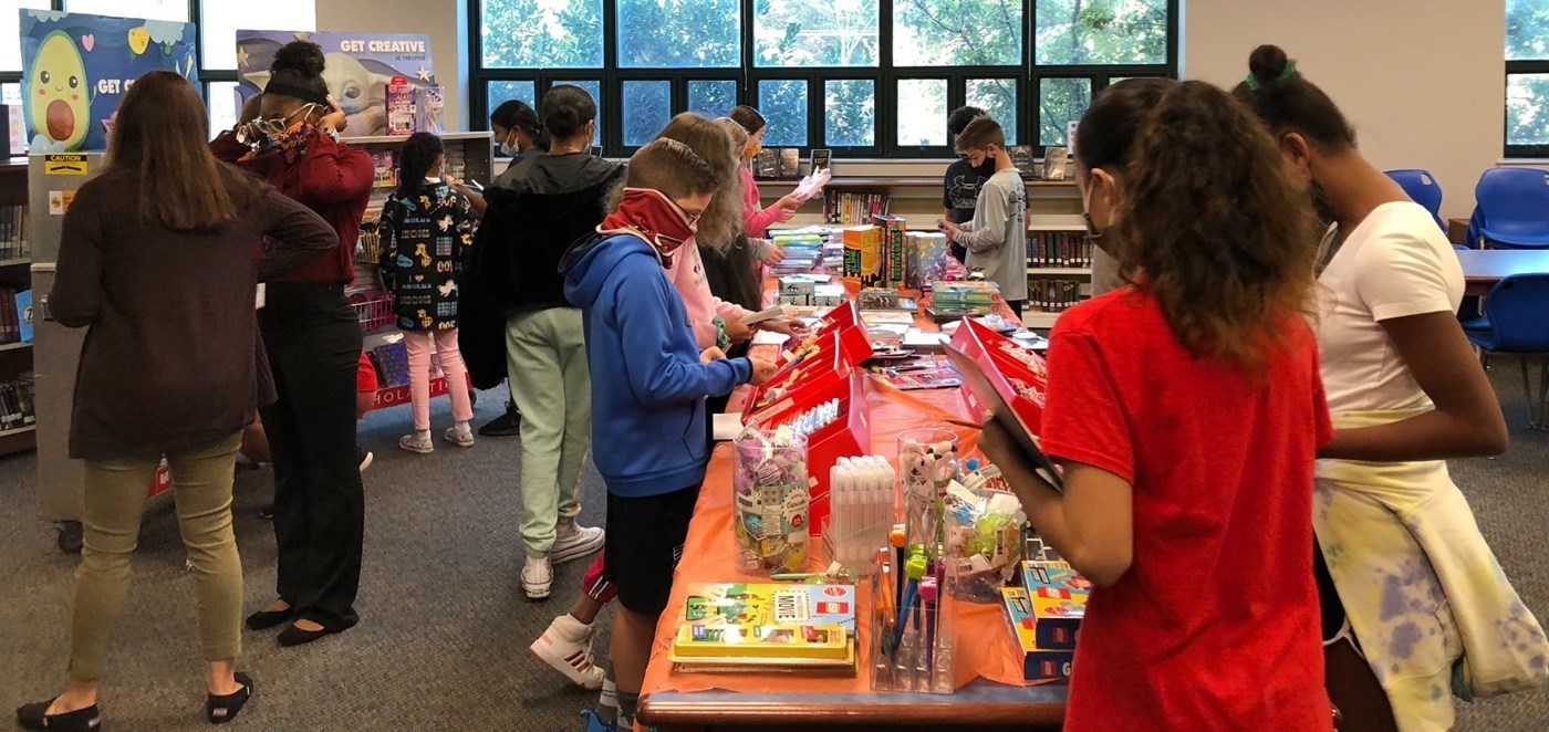 Students gathered around a table at Scholastic Book Fair