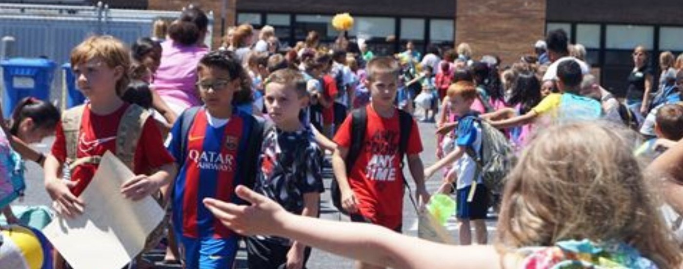 Students walking with backpacks on, in front of school building