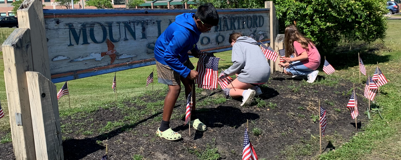 Students placing American flags around school sign
